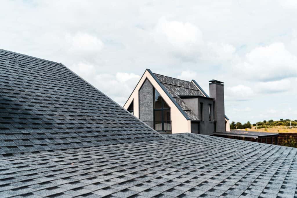 a roof with shingles and a house in the background.